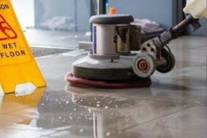 Pest control worker in protective suit spraying insecticide on furniture indoors