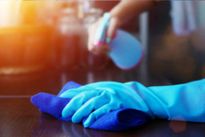 Pest control worker in protective suit spraying insecticide on furniture indoors